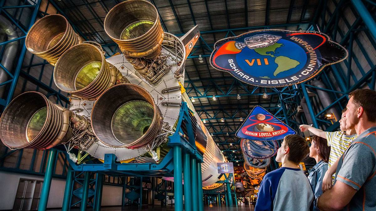 father with boys with child pointing while looking at rocket at Apollo Saturn V Rocket Center in Kennedy Space Center Visitor Center, Orlando, Florida, USA